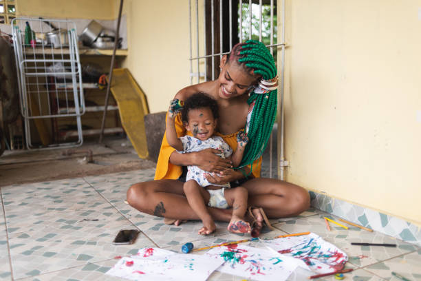 Mother and her baby boy with dirty hands and faces painting for fun at home