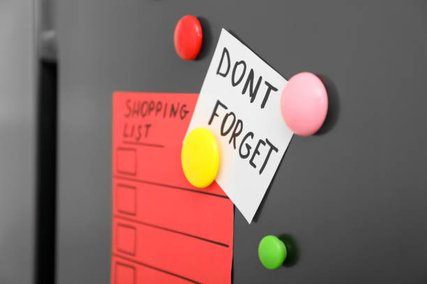 istock Note with phrase DON'T FORGET, shopping list and magnets on refrigerator, closeup 1335000427