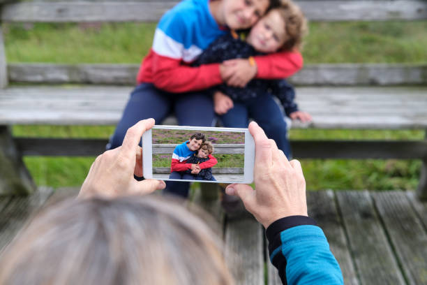 Mother taking a photo of her two children with her mobile phone stock photo