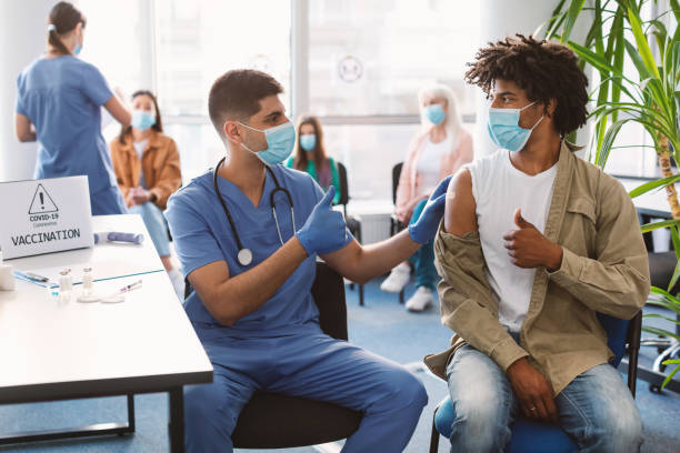 istock Vaccinated Black Guy And Doctor Gesturing Thumbs-Up At Clinic 1335002810