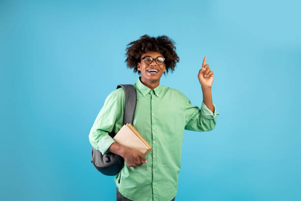 istock Wow, eureka. Overjoyed african american student guy having creative idea, pointing finger up on blue studio background 1335002874