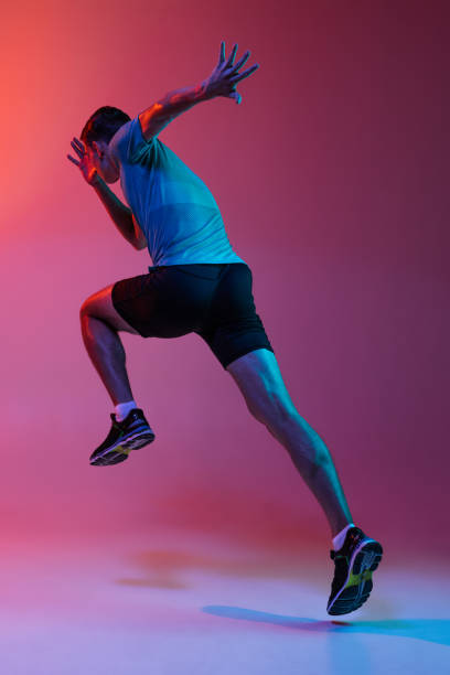 코카서스 프로 남성 선수의 포트랫, 파란색 네온 필터, 빛핑크 스튜디오 배경에 고립 된 주자 훈련. 근육질의, 스포츠 사람. 백 뷰 - muscular build sprinting jogging athlete 뉴스 사��진 이미지
