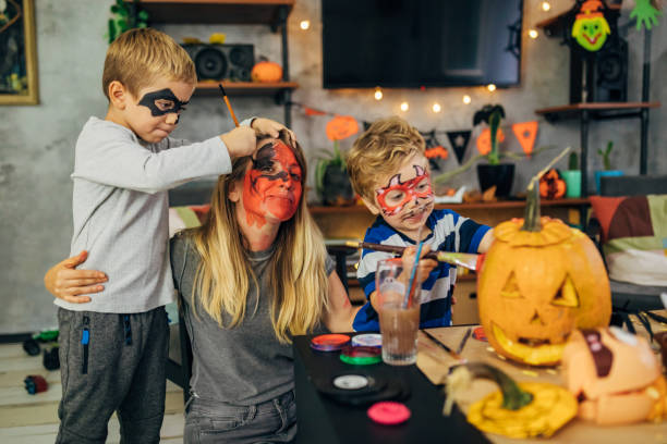 Fun family night, during Halloween Eve Creative mother with her playful sons, having a fun time, while making the Halloween decoration, enjoying every moment of it halloween face paint stock pictures, royalty-free photos & images