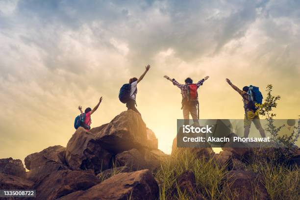 Adventure Team Traveler Successful Climbing Up To Mountain Cliff Under Gold Sunrise Stock Photo - Download Image Now