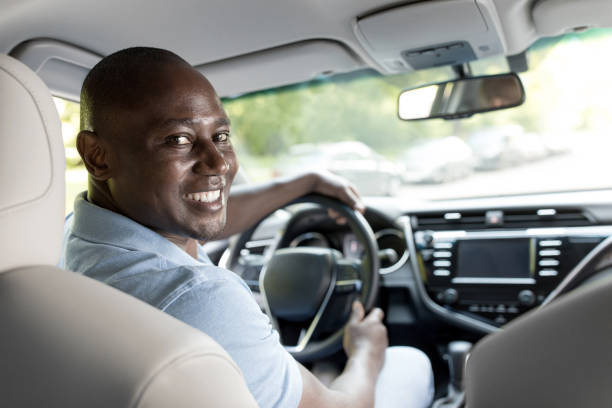 istock Smiling black guy driver sitting inside brand new car 1335009628