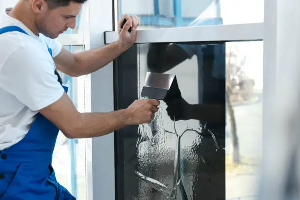 Photo of Professional worker tinting window with foil indoors