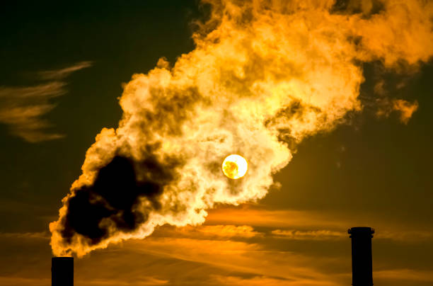 Flaming Inferno The sun shines through the exhaust gases of a power plant climate justice photos stock pictures, royalty-free photos & images