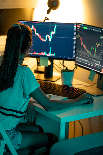 Woman Looking Stock Market Graph on Computer Monitors. Depicts TradingView financial market chart.