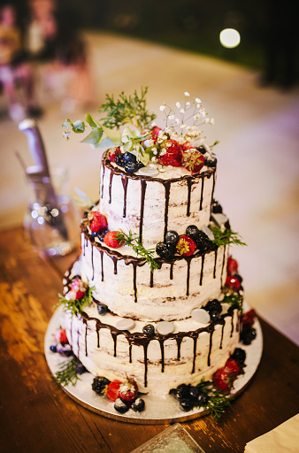 Luxurious desert table with tired white cake with flower, decorated cookies, and cupcakes. Neutral tones