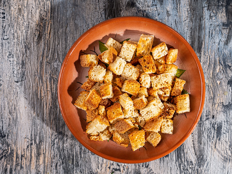Toasted white bread croutons on a ceramic brown plate top view