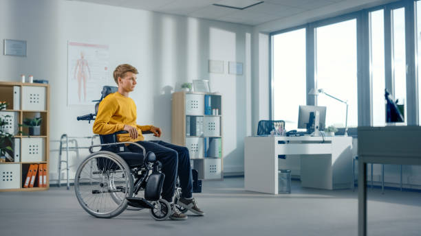 病院理学療法:足の怪我をした決定的な若者が車椅子に座っています。リハビリテーションの奇跡、強い心、意志力、専門医。 - hospital physical injury patient men ストックフォトと画像