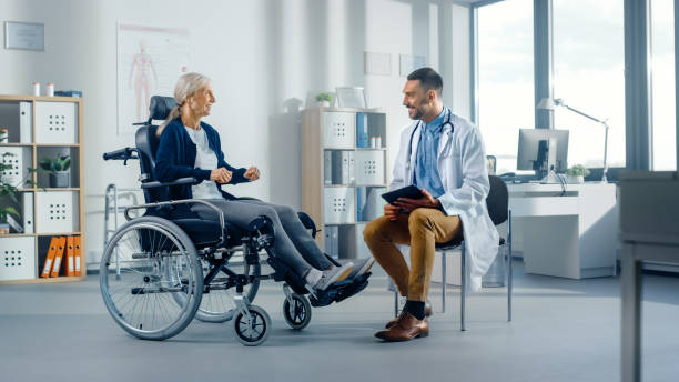 hospital physical therapy: strong senior female in wheelchair, talks to a friendly rehabilitation physiotherapist doctors gives advice, plans rehabilitation treatment for determined disabled patient - physical checkup imagens e fotografias de stock