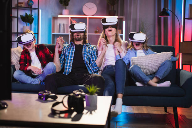 ソファでゲームをしているvrゴーグルで4人の興奮した家族 - gamer watching tv adult couple ストックフォトと画像