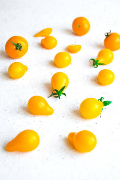 Small yellow tomatoes on white background. Closeup image of yellow pear tomatoes. Organic healthy food. Vertical orientation stock photo