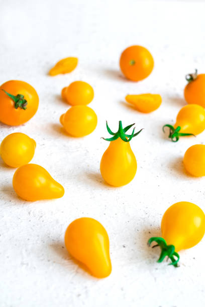 Small yellow tomatoes on white background. Closeup image of yellow pear tomatoes. Organic healthy food. Vertical orientation stock photo