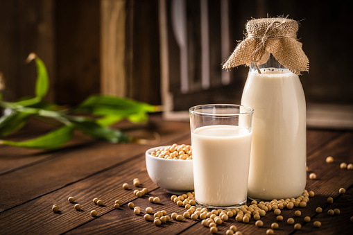 Glass and bottle full of soy milk on a wooden table