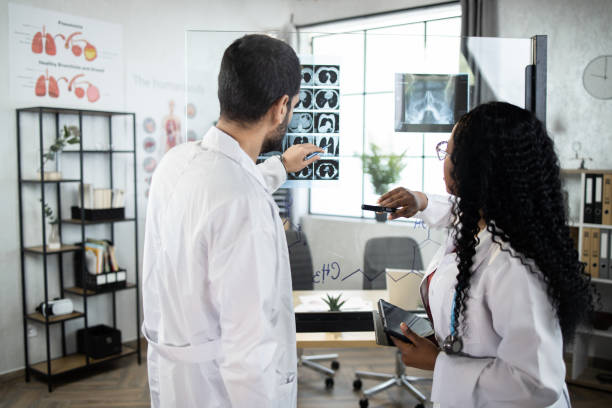 istock Two qualified multiethnic doctors, standing near the office glass board and interpreting CT scan 1335026937