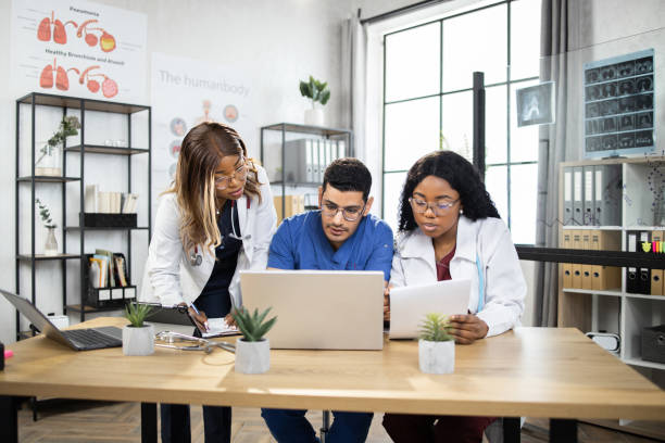 istock three multiracial doctors, working together with laptop, while sitting at the table in modern clinic 1335026969