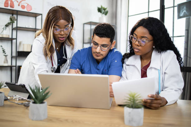 istock Three multiracial doctors having conference at hospital, working with laptop pc 1335026975
