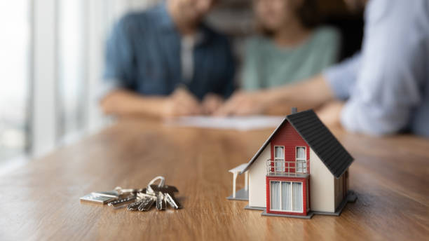 istock Close up of key and tiny toy house on table 1335027169