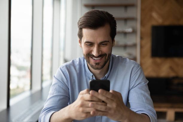 istock Happy excited male smartphone user reading, texting, smiling at screen 1335027254