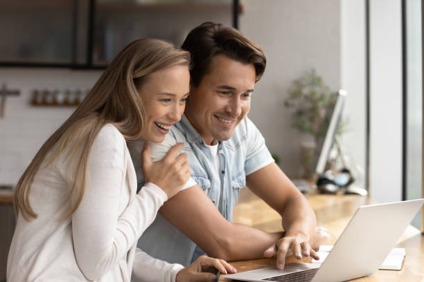 istock Happy married couple using laptop together at home workplace 1335027330