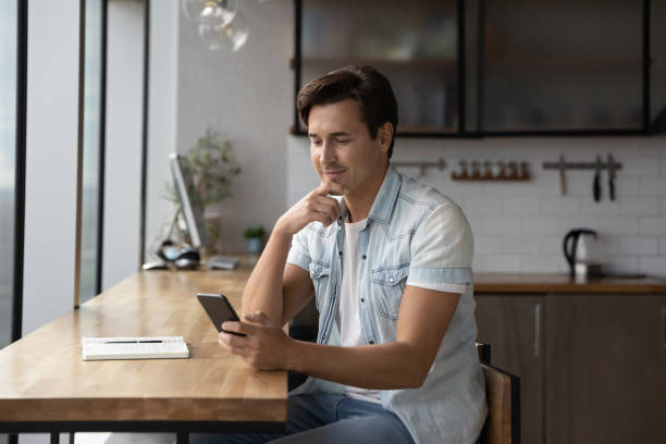 istock Happy thoughtful millennial guy using app, online service on smartphone 1335027334