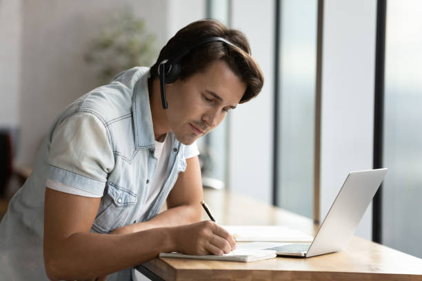 istock Focused adult student guy wearing headphones attending virtual class 1335027341