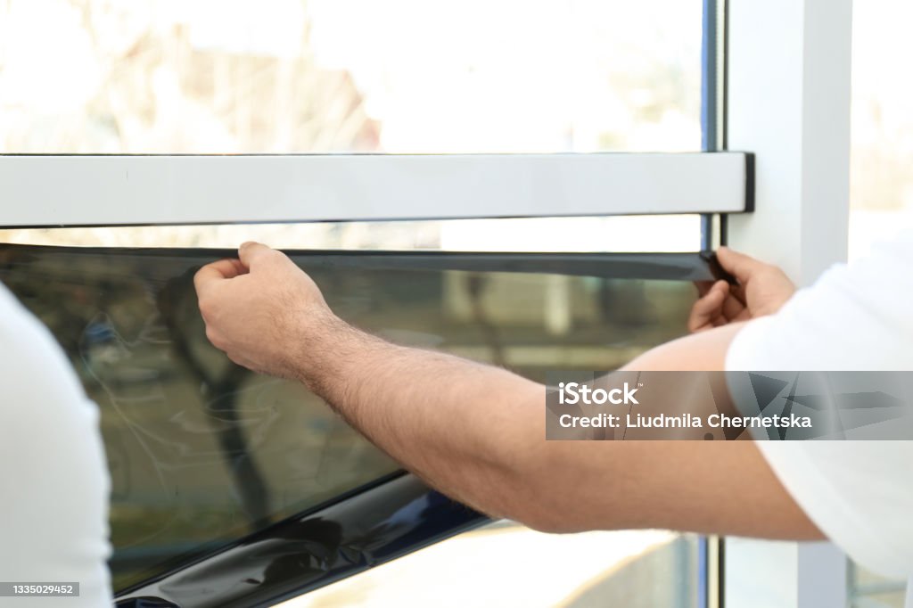 Professional worker tinting window with foil indoors, closeup Window Stock Photo