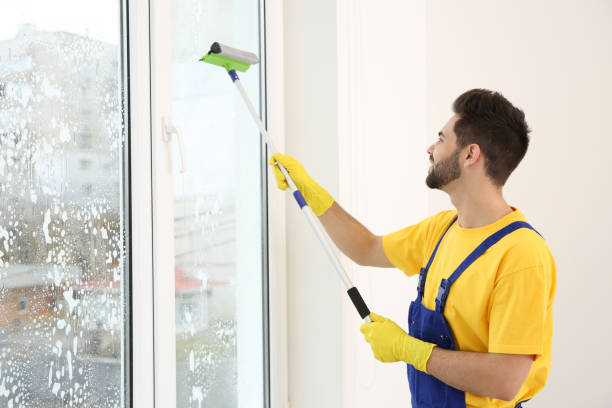 istock Professional young janitor in uniform cleaning window indoors 1335029732