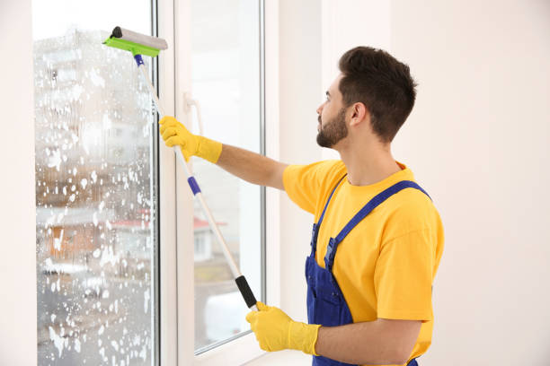 istock Professional young janitor in uniform cleaning window indoors 1335029867