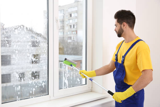 istock Professional young janitor in uniform cleaning window indoors 1335031416