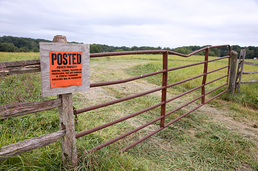 No trespassing sign on fence, indicating; Private Property, No to, Hunting, Fishing, Trapping, or Trespassing.