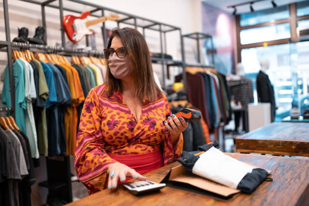 istock Saleswoman using calculator at clothing store 1335032814