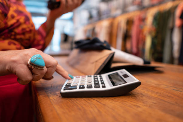 istock Saleswoman using calculator at the checkout counter 1335032852