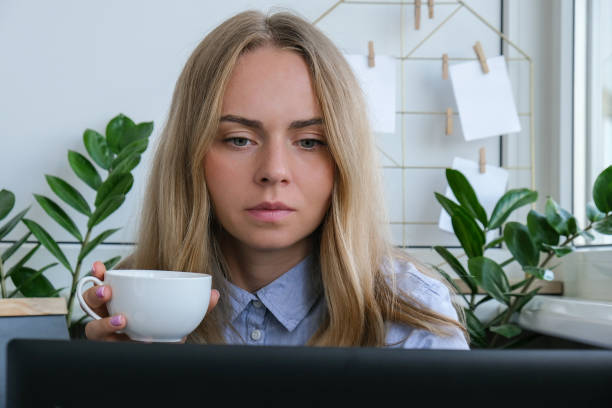 Young woman drinking coffee working on a computer at home, calculating monthly exspences, mortgage payments, doing home budgeting. Business woman working on her laptop. Online conference tutoring. Online education student mujer joven bebiendo café trabajando en una computadora en casa, calculando exspences mensuales, haciendo presupuestos caseros. mujer de negocios que trabaja en su computadora portátil. tutoría en conferencia online. estudiante de educación en línea