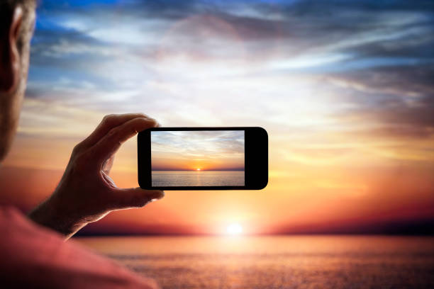 câmera de smartphone fotografando um pôr do sol do outro lado do mar nas férias - photo messaging telephone photographing camera - fotografias e filmes do acervo