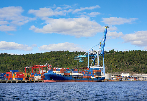 Oslo, Norway - August 2, 2021   Oslo container terminal with large crane and container ship.