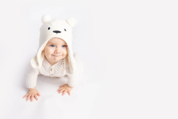 baby crawls in a warm suit and hat on a white isolated background, space for text