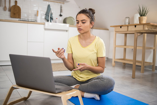 Beautiful, young woman preparing for her online exercise class.