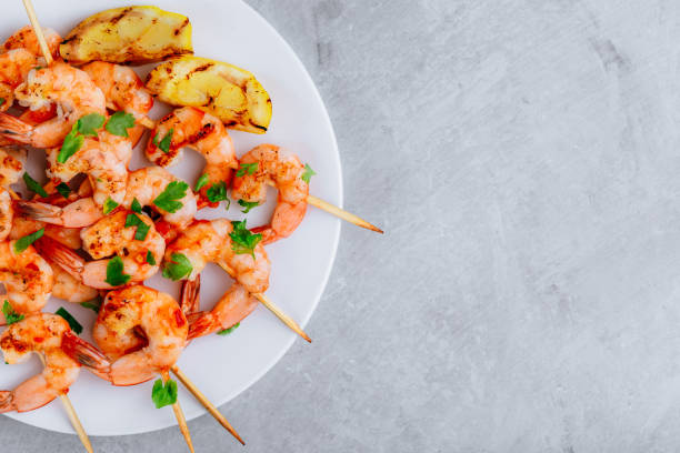 istock Grilled Lemon Shrimp Skewers in plate on gray stone background. 1335044575