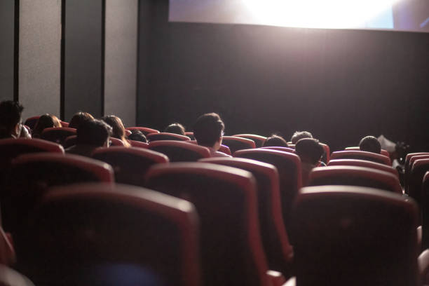 Rear view Asian group of audience watching movie in cinema enjoying the show. stock photo