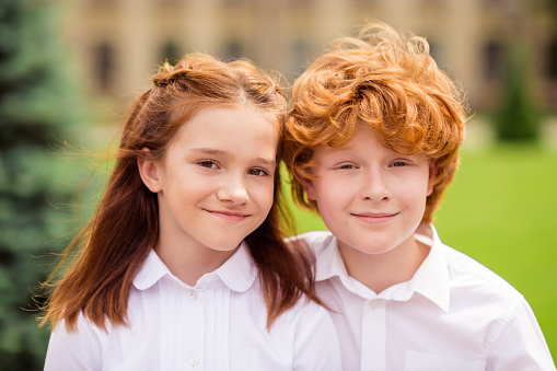 Photo of two positive nice ginger schoolkids look camera cuddle smile wear white shirt uniform park outdoors