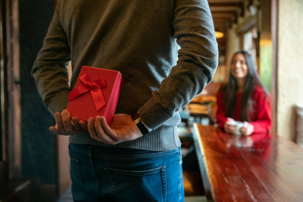 hombre sorprendiendo a la mujer con un regalo mientras celebra san valentín en un restaurante - valentine present fotografías e imágenes de stock