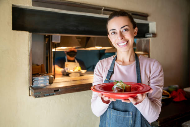 istock Happy waitress serving food at a restaurant 1335052530