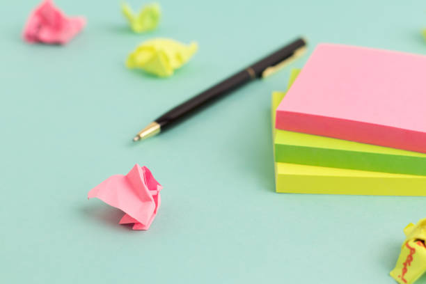 crumpled papers, pen and empty colorful sticky note paper on turquoise background. selective focus. - adhesive note note pad message pad yellow imagens e fotografias de stock