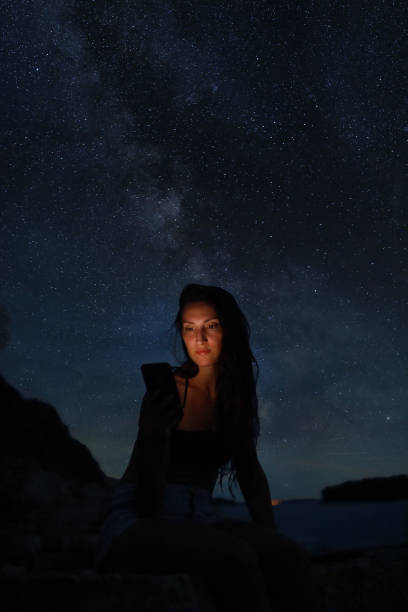 istock Woman sitting on the beach under the starry sky 1335057235