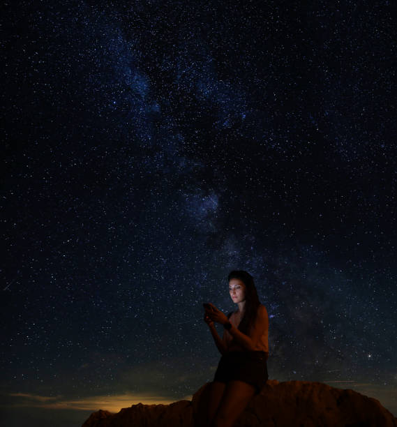 istock Woman sitting on the beach under the starry sky 1335057891