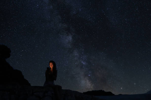 istock Woman sitting on the beach under the starry sky 1335058030