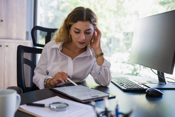 businesswoman signing legal document in office, using digital tablet - condition text magnifying glass contract imagens e fotografias de stock